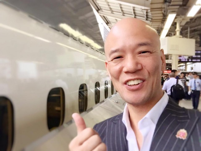 明るい笑顔で相手にエネルギーを差し出す鴨頭嘉人
