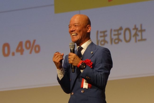 笑顔でマイクを持ち、オンラインでも明るく話す鴨頭嘉人