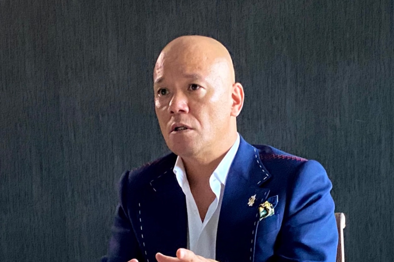 着席して両手で丁寧に説明する鴨頭嘉人