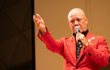 観客へ手を伸ばして力強く話す鴨頭嘉人