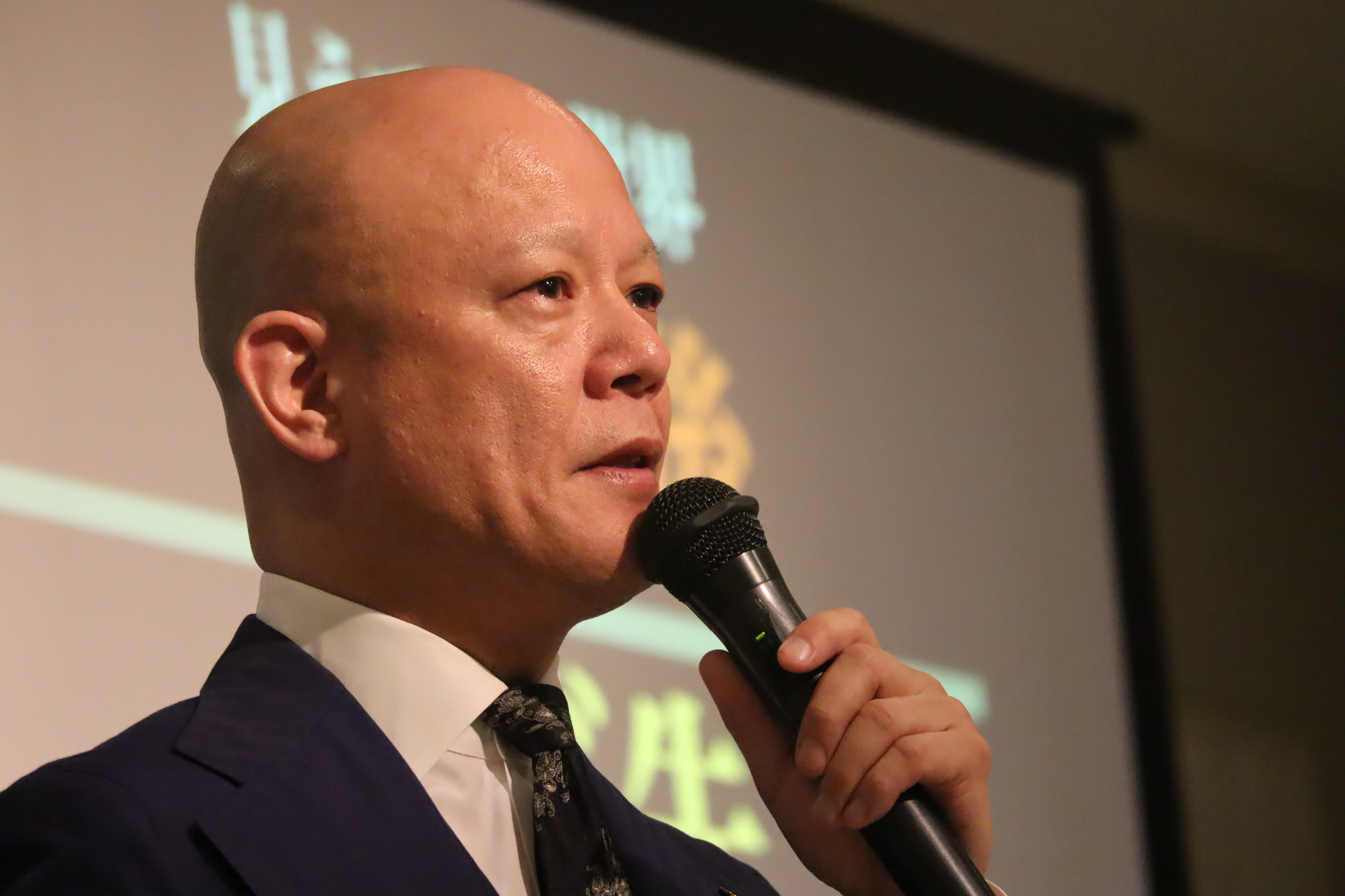 フォーマルな会場で考えを整理して話す鴨頭嘉人