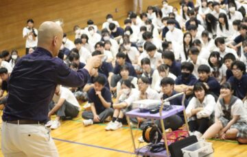 学校の体育館で生徒に向けて話す鴨頭嘉人