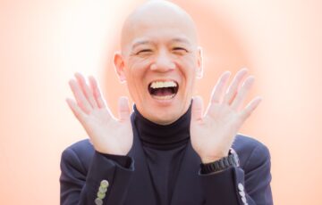 両手を開き、明るい笑顔を見せる鴨頭嘉人