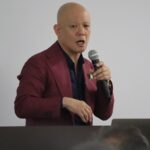 講座会場の演台でマイクを持って話す鴨頭嘉人