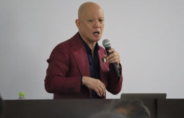 講座会場の演台でマイクを持って話す鴨頭嘉人