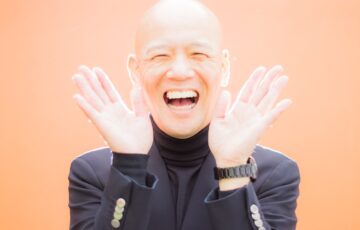 両手を開いて明るい笑顔を見せる鴨頭嘉人