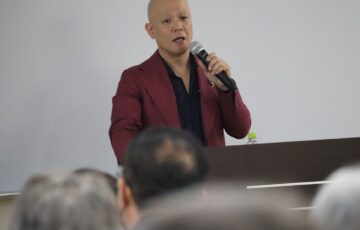 教室で受講生に向けてマイクを持って話す鴨頭嘉人