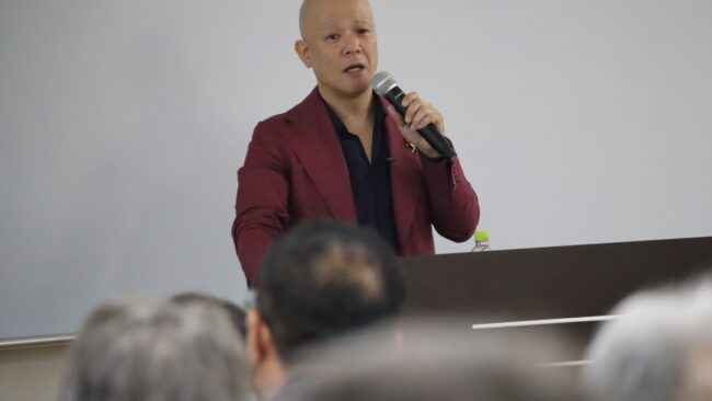 教室で受講生に向けてマイクを持って話す鴨頭嘉人