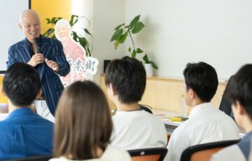 受講生の前で笑顔を見せながら話す鴨頭嘉人
