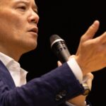 講演で手を差し出しながら聴衆へ語りかける鴨頭嘉人